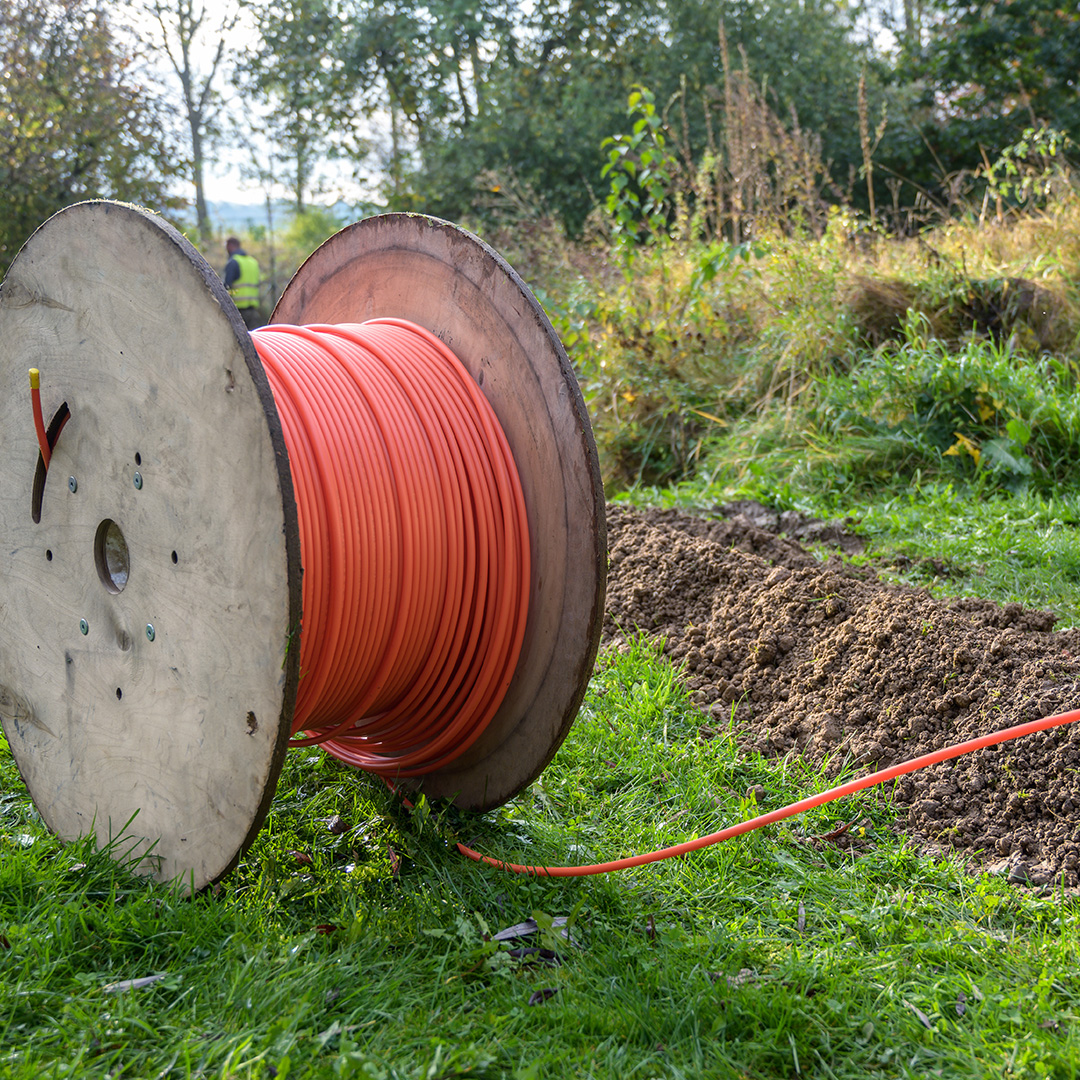Spool of fiber optic cable next to a trench